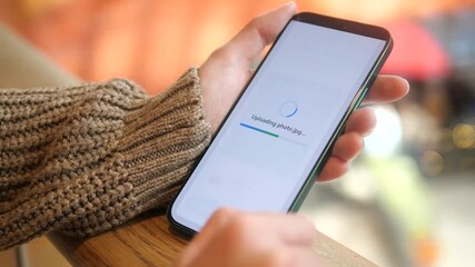 A modern professional uses her mobile device to effortlessly back up memories to the cloud while in a shopping mall. This video demonstrates the convenience of accessing and saving important files