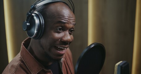 Male Voice Actor Delivering Dynamic Film Dubbing. Wearing Headphones and Facing Studio Microphone With Pop Filter, Man Records Expressive Lines With Strong Character Emotion and Vocal Precision.
