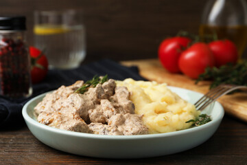 Delicious beef stroganoff with mashed potatoes and thyme served on wooden table, closeup