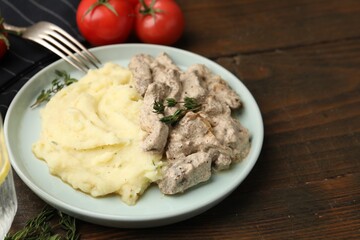 Delicious beef stroganoff with mashed potatoes and thyme served on wooden table, closeup. Space for text