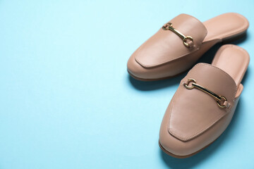 Pair of stylish mule shoes on light blue background, closeup. Space for text