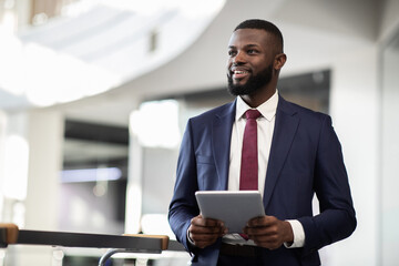 Cheerful young bearded african american man manager walking by office building corridor, holding...