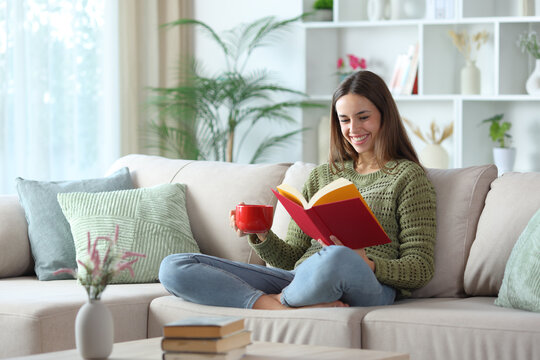 Happy woman in green drinking coffee and reading a paper book