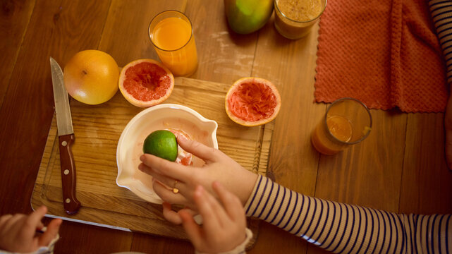 Citrus squeezing close-up with orange juice glass and fresh fruit in warm cozy kitchen. Concept of drink advertising, healthy homemade visuals and emotional lifestyle warmth. - Powered by Adobe