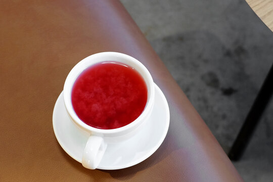 Cup of delicious cranberry and berries tea. Hot herbal red tea on the brown leather chair in cafe.