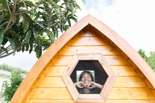 Woman smiling through bee sauna window with natural backdrop