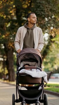 A proud parent strolls with their baby in a stroller down a tree-lined path. Capture the quiet joy of a father's walk. 