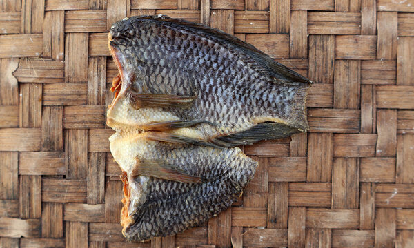 Salted tilapia fish (Ikan Nila Asin) on traditional woven bamboo tray