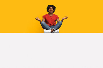 A joyful individual sits cross-legged on a white surface, surrounded by a vibrant yellow wall. The...