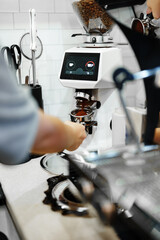 Barista prepares espresso with coffee machine in a cozy cafe setting during the morning rush
