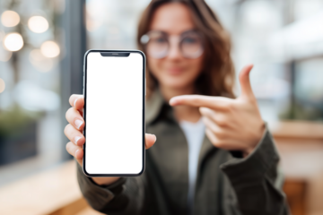 A young woman holding a smartphone toward the camera while pointing at its blank screen.