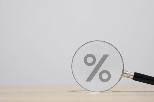 Magnifying glass focusing on a percentage symbol, representing interest rates, financial analysis, loan comparison, savings growth, and economic decision-making in business and finance concepts.