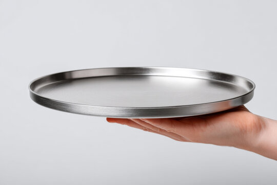 Close-up of a waiter's hand holding an empty metal tray on a white background. Restaurant employee concept.