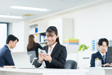 オフィスでスマホを使う若いビジネスウーマン
