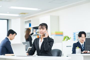 オフィスで電話する若いビジネスウーマン