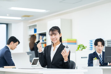 オフィスでガッツポーズする若いビジネスウーマン