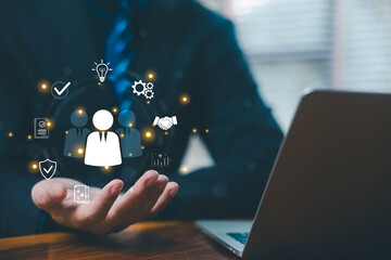 Businessman holding digital HR icons representing people management, employee relationship, teamwork, recruitment strategy, and modern human resources solutions in a digital business environment.