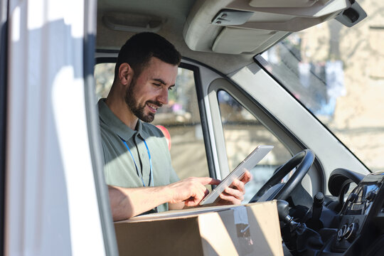 close up shot of Delivery man using digital tablet inside van