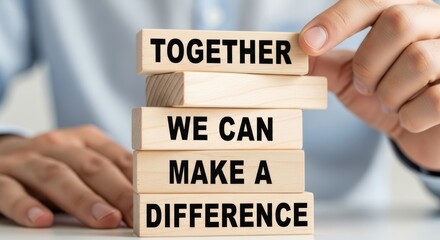 Teamwork for Making a difference: A close-up shot of a person's hands carefully arranging wooden blocks. Each block carries one word of a powerful message inspiring unity.