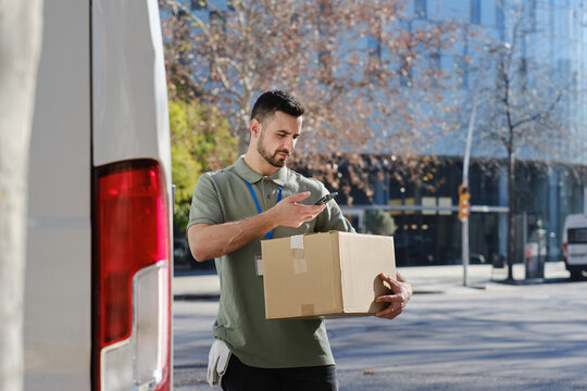 Delivery man scanning package with phone for logistics tracking