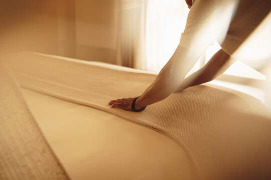 Hotel staff making the bed in a sunlit room with a cozy atmosphere