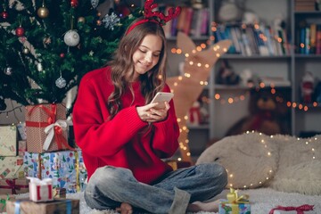 Beautiful christmas girl writing text message on phone
