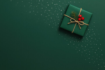 Christmas present with ribbon and red berries on green background