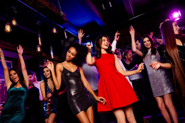Energetic party night on the dance floor with stylish dancers in bright dresses and neon club lights