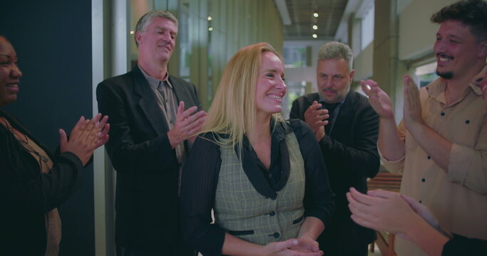 Cheerful business team clapping for female colleague in modern office hallway, diverse coworkers expressing recognition and appreciation for success - Powered by Adobe