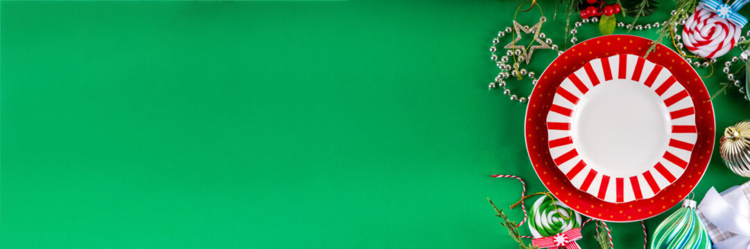 Christmas and New Year cutlery background, holiday table setting, festive dinner brunch invitation menu. Red white candy cane styled plate and Christmas baubles on bright green background