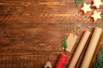 Christmas wrapping flat lay with paper rolls, rope, gift tags and scissors on dark wooden desk. Copy space for text.