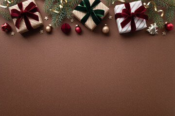 Golden gift or present boxes with velvet red and green ribbon with festive decoration on brown background for Christmas or New Year greeting card.