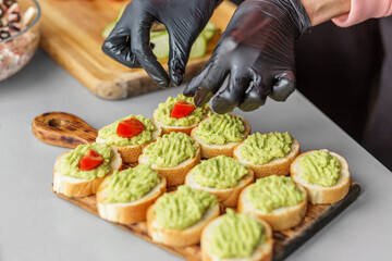 Chef Garnishing Avocado Bruschetta with Tomato on Wooden Board