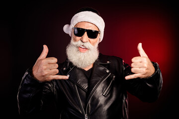 Cool Santa rocker in leather jacket with white beard and sunglasses giving double thumbs up in...