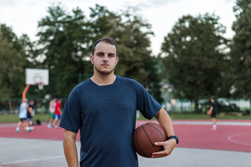 A man stands on a basketball court, preparing to shoot while others play in the background.