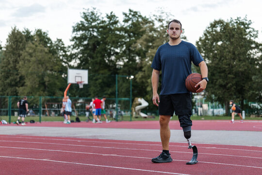 A man with a prosthetic leg showcases his basketball skills on a sunny day outdoors.