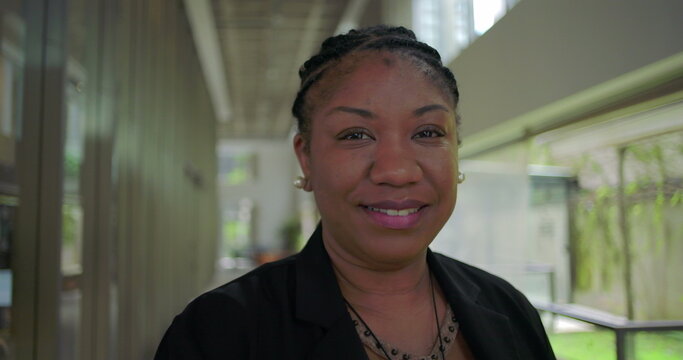 Close up of African American woman smiling with confidence and warmth in modern office hallway authentic expression in professional business environment - Powered by Adobe