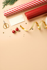 Christmas gift wrapping with red and white striped wrapping paper, ribbon, baubles, scissors, cedar spruce on beige backdrop. Copy space.