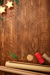 Christmas wrapping background with paper rolls, rope, gift tags and scissors on dark wooden desk. Copy space for text.