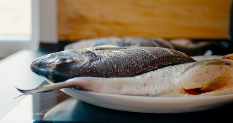 Seasoned sea breams resting on white ceramic plate, showcasing fresh caught seafood ready for the Grill