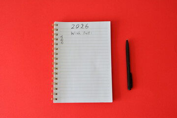 2026 Wish List on a Notebook with a Pen on Red Background top view