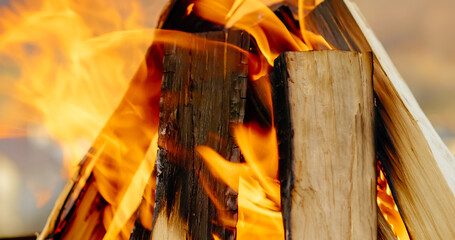 Crackling wood fire burning intensely, casting orange and yellow flames while preparing outdoor barbecue grill with intense heat and energy