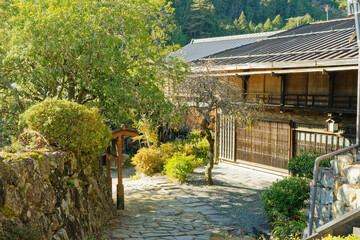 Stone path, garden shrubs and traditional wooden house in Tsumago-juku, Nagano, Japan