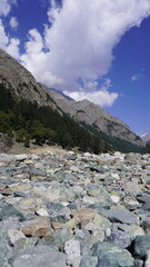 Scenic rocky foreground with large boulders and towering mountain backdrop beneath blue sky, scale concept.