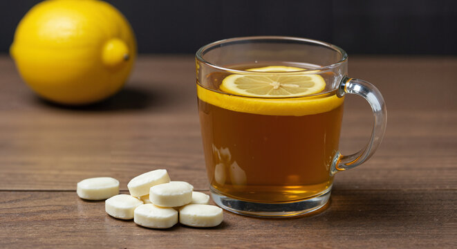 Herbal tea with lemon slice and tablets on wooden table  