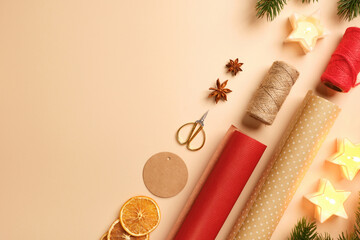 Items for gift wrapping with wrapping paper, rope, dried oranges, spices on beige background. Place for text or design.