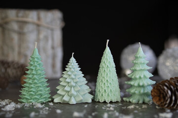 Burning candle in shape of Christmas tree and decor on dark background