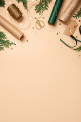 Gift wrapping background. Paper rolls, twine, gift tag, and gold stars on beige table. Copy space for holiday text or design.
