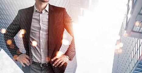 Confident businessman with hands on hips blended with tall skyscrapers and city lights on bright...