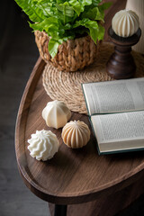 Decorative Sculpted Candles on Wooden Table With Plant and Open Book